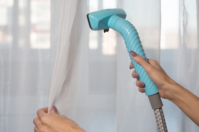 The girl holds a steamer for curtains in her hand