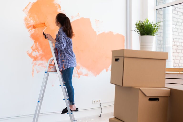 Pretty young woman with painting roller indoors. Redecoration, renovation, apartment repair and refreshment concept